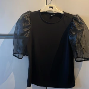 Svart partytopp str L - Partytopp från ginatricot i svart med kort puffärm. Funkar för en med storlek M också. Använt en gång.