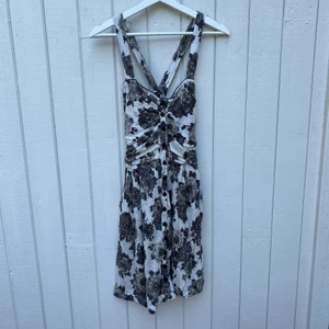 Blommig knälång klänning - Knälång klänning med knappar, korsade band i ryggen och dolda fickor. 