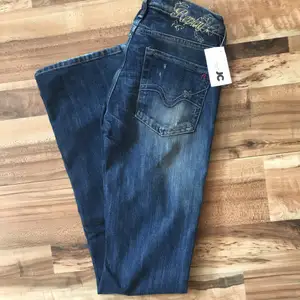 Ett par helt nya Replay Jeans i färgen mörk blå. Modellen är Bootcut Denim. Fickorna där back har sy detaljer. Storleken är W25 och L32. Midjemåttet är 76 cm och innebenslängden är 80 cm.