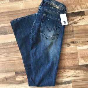 Replay Blue Jeans - Bootcut - Ett par helt nya Replay Jeans i färgen mörk blå. Modellen är Bootcut Denim. Fickorna där back har sy detaljer. Storleken är W25 och L32. Midjemåttet är 76 cm och innebenslängden är 80 cm.