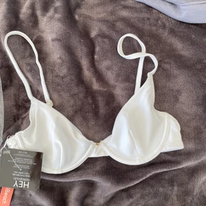 Supersnygg bikinitopp  - Så fin vit bikinitopp med gulddetaljer från nelly som jag tyvärr beställde i en för liten storlek och ej kunde byta. Helt oanvänd med lapp och påse kvar. Köpare står för frakten <3