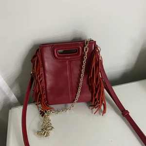 Maje väska röd  - Hej! Jag säljer nu min röda maje mini väska i skinn. Den är liten, 16x13cm, och köpt hösten 2020 i NK Stockholm. Den är knappt använd och i väldigt bra skick, förutom några slitningar på handtaget, (se bild 3). Har både axelband och en kedja i guldliknande färg som man kan variera mellan. Pris kan diskuteras. Köpt för ca 2100