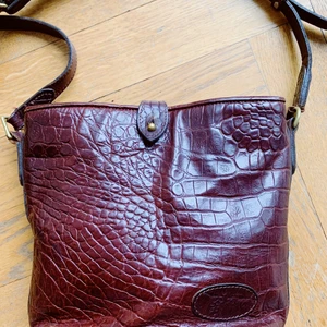 Mulberry vintage axelremsväska - Vintage axelremsväska från Mulberry säljes. Jättefin men kommer inte till användning. Brunt crocopräglat skinn/läder med bronsfärgade metalldetaljer. Lång justerbar axelrem - kan både användas cross-body eller längst sidan. Finns ett litet fack med dragkedja invändigt. Klädd med klassiskt rutigt Mulberry-tyg. Använd men gott skick!  Storlek mäter cirka 17 x 15 cm 🌞