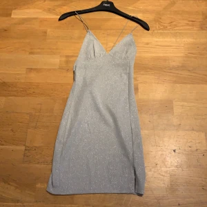 Glittrig klänning i silver - Jättesnygg glittrig klänning i silver från H&M divided. Bara använd en gång. Eftersom H&Ms hemsida bara hade kvar den i blå fick jag ta den, bara så man ser hur den ser ut på. Det är exakt en likadan fast silver som jag säljer som man kan se på första bilden.