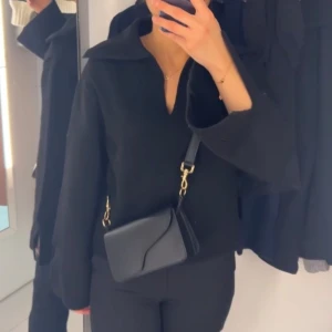 Svart stickad tröja - Stickad svart tröja med krage och vida armar med slits från Gina Tricot. Bra passform. Använd ett par gånger.