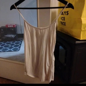 Vit linnetopp från H&M Basics - Enkel och stilren vit linnetopp från H&M Basics i storlek S. Tunt material med smala axelband och rak passform, perfekt för varma dagar eller som lager under andra plagg. Snygg att matcha med jeans eller kjol.