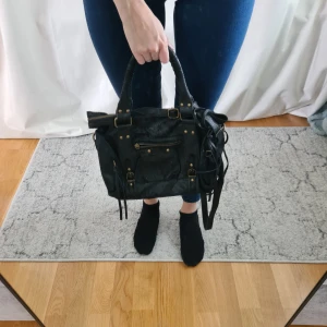 Svart city bag i skinn - Svart city bag i skinn. Ca 28x23x13 cm. Det finns inget snöre på fickan där fram men det påverkar inte användningen. Inhandlad i Italien.