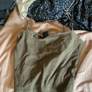 Olivgrön linnetopp med smala axelband från Gina tricot - Säljer en enkel och stilren olivgrön linnetopp med smala axelband. Toppen är ärmlös och har en rak, croppad passform som sitter snyggt på kroppen. Perfekt att matcha med jeans eller kjol för en chill look. De står xl men passar mig som s hahaha