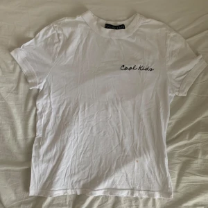 vit baby tee / t-shirt - Snygg vit t-shirt med broderad text ”cool kids” från Urban Outfitters. Den har två små foundation fläckar, en på framsidan och en på baksidan. Men går nog att få bort. Använd 1-2 gånger 🤍  Jag säljer den även tillsammans med en annan topp för 15 kr. Kolla in min profil om du är intresserad!