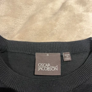 Svart stickad tröja från Oscar Jacobson - Klassisk svart stickad tröja från Oscar Jacobson. Tröjan har rund halsringning och långa ärmar, perfekt för lager-på-lager. Tillverkad i Italien med en mjuk och skön känsla. Enkel och stilren design som funkar till det mesta. Tröjan är knappt använd kanske 2-3 ggr inga defekter köpt för 1500kr mitt pris 600kr