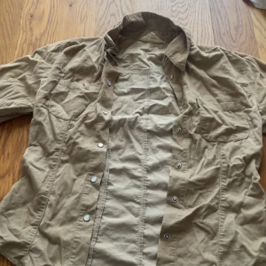 Beige manchesterskjorta från Lemon - Snygg beige skjorta från Lemon i manchestertyg. Skjortan har klassisk krage, tryckknappar framtill och två bröstfickor. Perfekt för lager-på-lager och passar till många olika stilar.