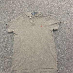 Polo Ralph Lauren pikétröja – Custom Fit (M) - Polo Ralph Lauren pikétröja – Custom Fit (M) Pris: 130 kr (pris kan diskuteras)  Snygg grå pikétröja från Polo by Ralph Lauren i modellen Custom Fit, storlek Medium. Klassisk design med röd broderad logga (polo-spelare) på bröstet. Tröjan är i fint skick och passar perfekt både till vardags och mer uppklädda tillfällen.  ✔️ skickas inom 24h ✔️ Bra skick ✔️ Normal passform (Custom Fit) ✔️ Tillverkad i 100 % bomull