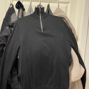 Svart långärmad half zip tröja - Svart långärmad tröja med hög krage och half zip-dragkedja framtill från selected homme. Enkel och stilren design som passar perfekt till lager-på-lager. Skön och mjuk känsla, perfekt för kyligare dagar. Enbart testad.