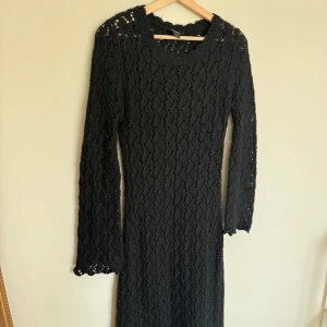 Svart stickad långklänning  - Svart långklänning från Monki i stickat material med snyggt hålmönster. Klänningen har lång ärm och rund halsringning.