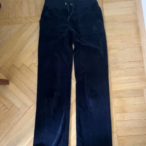 Mörkblåa juicy - Mörkblåa juicy byxor i mjukt sammetstyg med  snörning i midjan. Byxorna har raka ben, stora fickor fram och bak med knappdetaljer. Väldigt sköna och i bra skick! Säljer då jag växer ur❤️