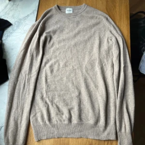 Beige kashmirtröja från John Henric - Supermjuk beige tröja i 100% kashmir från John Henric. Klassisk rund halsringning och ribbade muddar vid ärmslut och nederkant. Perfekt för dig som vill ha en stilren och lyxig look med en skön känsla. Passar lika bra till jeans som till kostymbyxor.