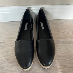 Svarta ballerinaskor/espadrillos från Blankens - Stilrena svarta ballerinaskor från Blankens i skinn med platt sula. Sidan har en snygg detalj med flätad kant i naturfärgad jute. Aldrig använda, så i nyskick men utan prislapp. 