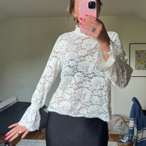 Vit spetsblus med blommönster - Superfin vit blus i spets med blommigt mönster och höga volangärmar. 