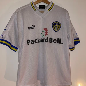 Leeds United vit matchtröja Puma - Klassisk Leeds United fotbollströja i vitt med blå . Replika på retrotröjan från säsongen 98/99 i bra skick. Storlek XL.