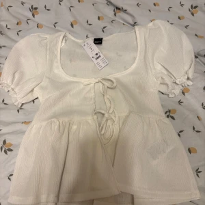 Vit blus med puff ärmar - Söt sommrig blus/topp från Gina. Säljer då den inte kommer till användning. Aldrig använd eller testad.