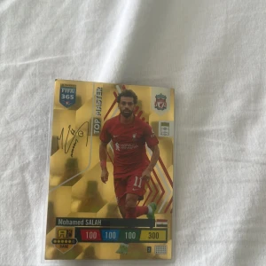 FIFA 365 Adrenalyn XL Top Master Mohamed Salah - Samlar du på fotbollskort? Här är ett exklusivt Top Master-kort med Mohamed Salah från Paninis FIFA 365 Adrenalyn XL-serie! Kortet är rare och har cool design med guldglans – perfekt för unga fans och samlare som älskar fotboll och Liverpool.