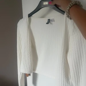 Vit kofta från Hm - Säljer en vit, croppad kofta från HM. Den är i storlek M men är mindre i storleken, aldrig använd.