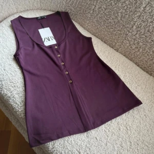 Vinröd topp från Zara - Snygg vinröd topp från Zara med knappar framtill. Perfekt att styla med jeans eller kjol för en trendig look. Ordinarie pris 300kr
