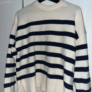 Randig stickad tröja från Zara - Superfin stickad tröja från Zara i beige med mörkblåa ränder. Oversized fit med breda ribbade muddar vid ärmslut och nederkant. Perfekt för lager-på-lager och chill vibes. Klassisk rund halsringning och långärmad modell.