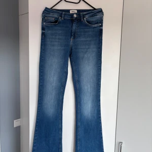 Blå bootcut jeans från ONLY - Snygga blå bootcut jeans från ONLY i medelblå tvätt. Jeansen har normal passform och är tillverkade i denimtyg. Dom är stretchiga med mjukt tyg. Helt nya och oanvända.