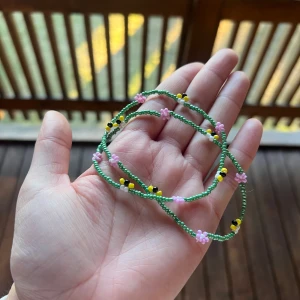 Pärlhalsband med blommor och bin!  - Supergulligt handgjort halsband med små gröna pärlor, dekorerat med rosa blommor och söta bin i gult, svart och vitt! Elastiskt band vilket gör att det passar de flesta, se sista bilden. Vid frågor är det bara att skriva!! 