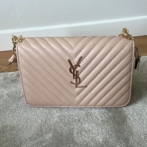En super fin rosa YSL väska med guld detaljer - Säljer denna superfina YSL väskan som är fejk. Den är rosa och har gulda detaljer och insidan av väskan är röd med massor av fak. Väskan har aldrig använts och har där med inga defekter på användning. Priset kan diskuteras.