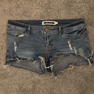 Blå slitna jeansshorts Noisy May - Snygga blå jeansshorts från Noisy May med slitna detaljer och fransig kant. Klassisk femficksmodell med låg midja och råa kanter för en cool, avslappnad vibe. Perfekta för varma sommardagar och festivaler. Pris kan diskuteras 💓