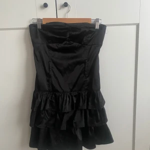 Bandeu klänning med volanger💞 - säljer denna supersnygga bandeu klänningen som är svart och har volanger där nere. den har en dragkedja på sidan av klänningen och är stretchig. säljer då den inte kommer till användning!👩‍❤️‍💋‍👩