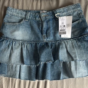 Blå jeanskjol med volanger - Blå jeans kjol med volanger från Gina Young.Aldrig använd 