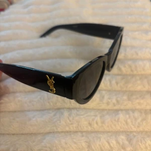 Svarta cat eye-solglasögon - Snygga svarta solglasögon YSL inspirerade med cat eye-form och breda skalmar. Guldig YSL-logga på sidorna ger en lyxig vibe. 💕