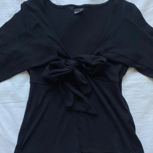 Svart knyttopp - Svart topp från Gina Tricot. Tyget har blivit knottrigt pga många tvättningar men de är inget som stör helheten! Toppen har en stor knytrosett framtill, långa ärmar och en figurnära passform💓