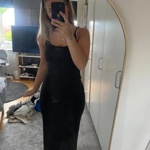 Svart långklänning med snörning - Supersnygg svart långklänning från NA-KD med smala axelband och figurnära passform. Klänningen har en öppen rygg med snörningsdetalj och lätt draperad urringning framtill. Perfekt för dig som vill ha en stilren och elegant look. Aldrig använd!