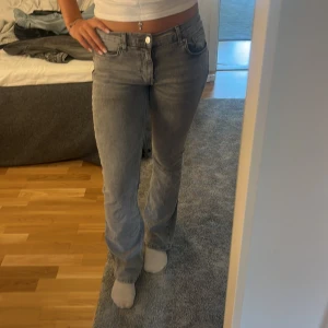Grå bootcut jeans  - Säljer ett par grå jeans med bootcut-modell och mid midja men det står att dem e Low waist. Jeansen har klassisk femficksdesign, knapp och dragkedja framtill samt snygg tvättad look. Perfekta för dig som gillar en avslappnad men ändå trendig stil.