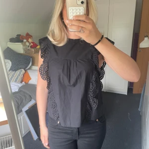 Svart blus med spetsvolang - Svart topp med ett väldigt fint material och fin passform. Använd fåtal gånger, 1-3.