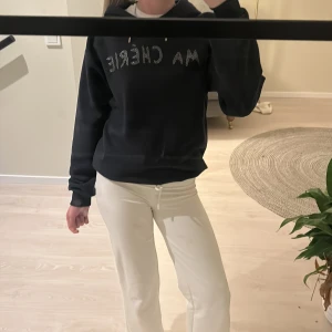 Mörkblå  hoodie från Gina Tricot - Säljer en mörkblå hoodie från Gina Tricot med texten 'MA CHÉRIE' i glittriga stenar på bröstet. Tröjan har en klassisk huva med dragsko och långa ärmar. Perfekt för en avslappnad stil.
