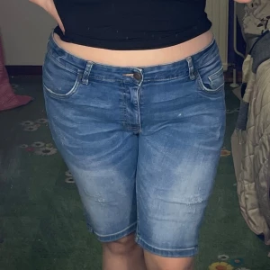 Blå jeansshorts  - Snygga blå jeansshorts med en klassisk femficksdesign. De har en bekväm passform och är perfekta för en avslappnad stil. Shortsen har en lätt tvättad look och stängs med dragkedja och knapp.