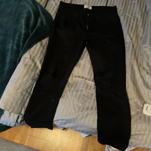 Svarta jeans från Acne Studios - Snygga svarta jeans från Acne Studios i modellen 'Thin Stay Cash'. De har en klassisk design med dragkedja och knapp framtill. Perfekta för en stilren look.