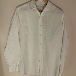 Vit kostymskjorta från Massimo Dutti (storlek M) - Säljer en stilren vit kostymskjorta från Massimo Dutti i storlek M. Skjortan har långa ärmar och knappar framtill. Perfekt för en klassisk look med bästa samt skönaste materialet som finns på marknaden. Nypris 1400kr