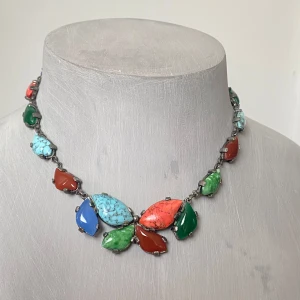 Färgglatt vintage halsband med stenar  - Unikt halsband med stora färgglada stenar i blått, grönt, rött och turkos. Stenarna är formade som blad och sitter i en metallkedja. Perfekt för att ge en färgklick till din outfit.