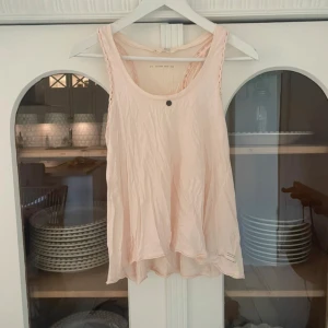 Ljusrosa linne från Odd Molly - Säljer ett ljusrosa linne från Odd Molly med flätade axelband och rund halsringning. Perfekt för varma dagar och en avslappnad stil. Linnet har en mjuk och bekväm passform.