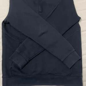 Mörk blå tröja med dragkedja från Dressmann - Säljer en lite använd svart tröja från Dressmann i storlek M. Tröjan har en praktisk dragkedja vid halsen och är tillverkad i en mjuk bomullsblandning. Perfekt för en avslappnad look.