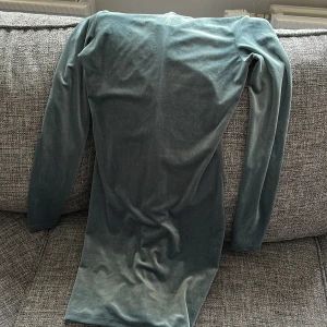 Grön klänning från H&M - Snygg grön klänning från H&M i mjukt material. Den har långa ärmar och en elegant passform som passar perfekt för olika tillfällen. Klänningen är i en vacker grön nyans som ger en stilren look.