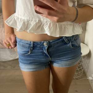 Snygga blå jeansshorts med låg midja och klassisk femficksdesign. Perfekta för varma sommardagar. De har en knapp och dragkedja framtill samt uppvikta benslut för en trendig look.