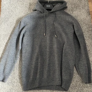 Khasmir - Säljer en stilren grå hoodie från Kashmir. Tröjan är tillverkad i ett mjukt material och har en klassisk design med dragsko i huvan. Perfekt för en avslappnad look.