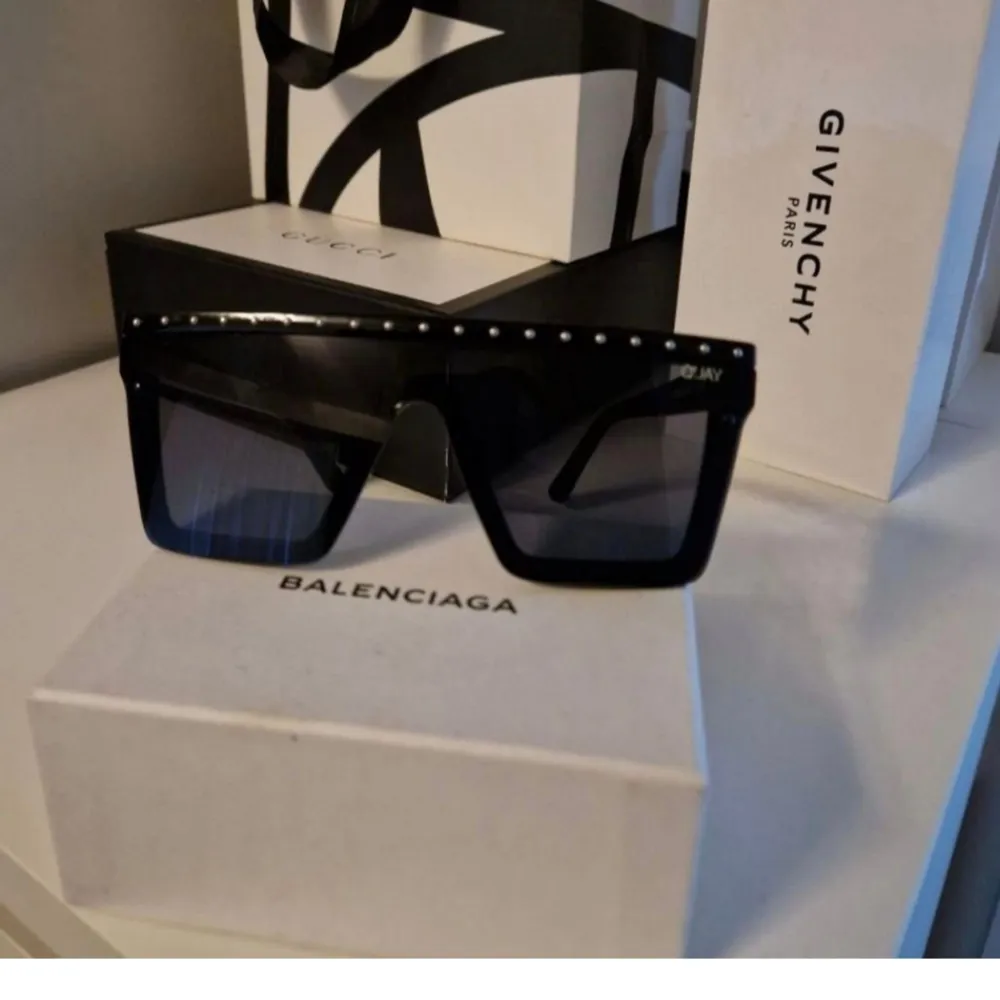 Snygga svarta solglasögon från Quay med en oversized design. Bågarna har små silverdetaljer längs överkanten som ger en extra touch av stil. Perfekta för att ge din look en modern och trendig känsla.. Asusteet.